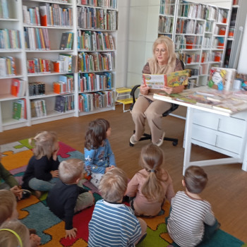 Dzieci słuchają pani, która czyta książkę. 